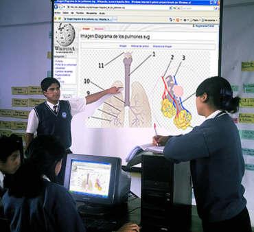 Alumnos exponiendo un tema de ciencias naturales con apoyo de una pantalla  ampliada de una computadora